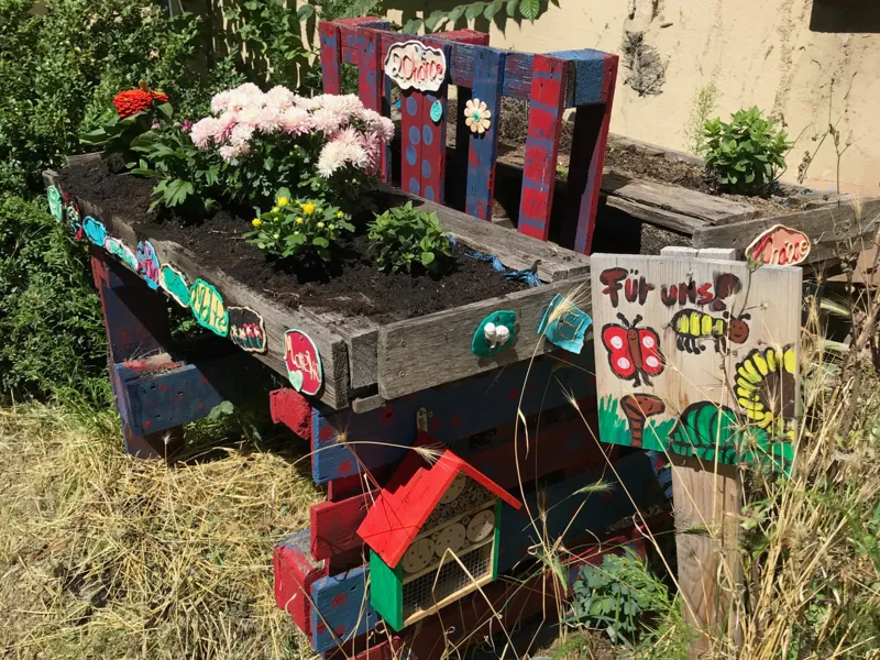 Ein Hochbeet ist mit bl&uuml;henden Blumen bepflanzt, Insekten finden Unterschlupf-M&ouml;glichkeiten,
